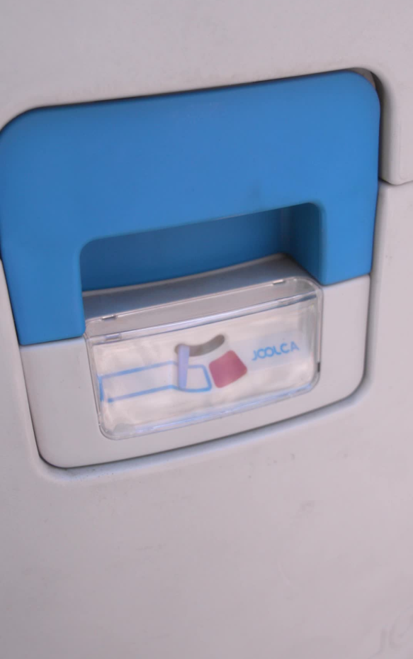 Close-up of a blue and white portable toilet urine indicator with a transparent cover showing a red and blue graphic and the brand name Joolca.