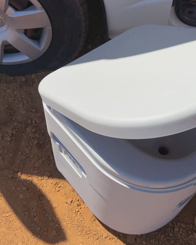 GottaGo sitting closed on dirt beside a vehicle wheel, its lid sealed flat onto the base.