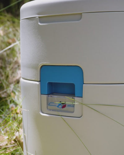 Close-up of a blue and white portable toilet urine indicator with a transparent cover showing a red and blue graphic and the brand name Joolca.