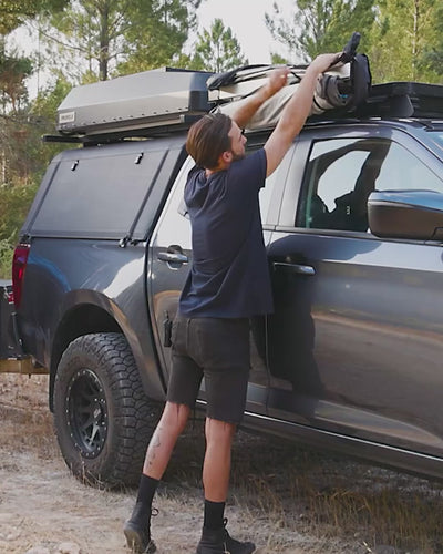 Man in a cap setting up the Joolca Ensuite Mounted Single tent in seconds.